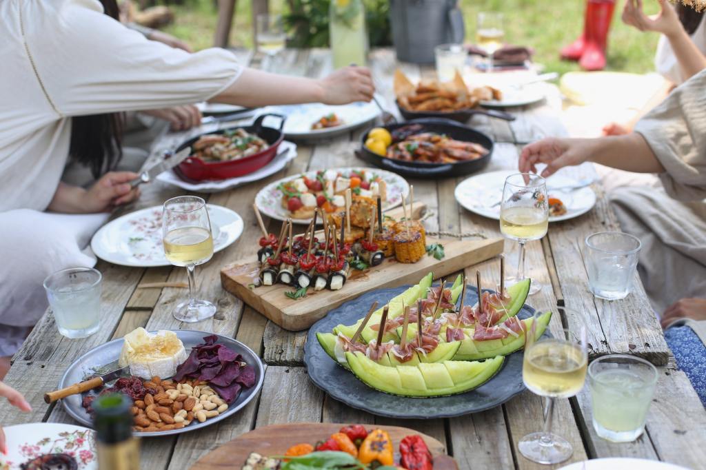 people enjoying a brunch, with appetizers, fruit, wine, cheese and nuts