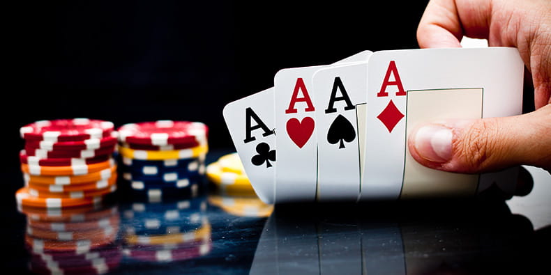Чоловік тримає покерну руку з чотирма тузами
