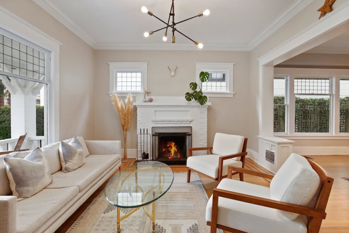 غرفة معيشة ذات ألوان محايدة مع مدفأة وكرسيين وأريكة