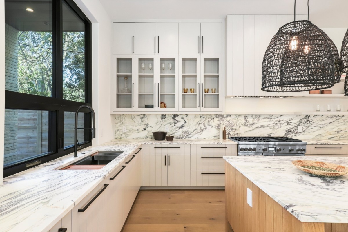 精美更新的厨房配有黑色硬件、白色花岗岩台面和木地板