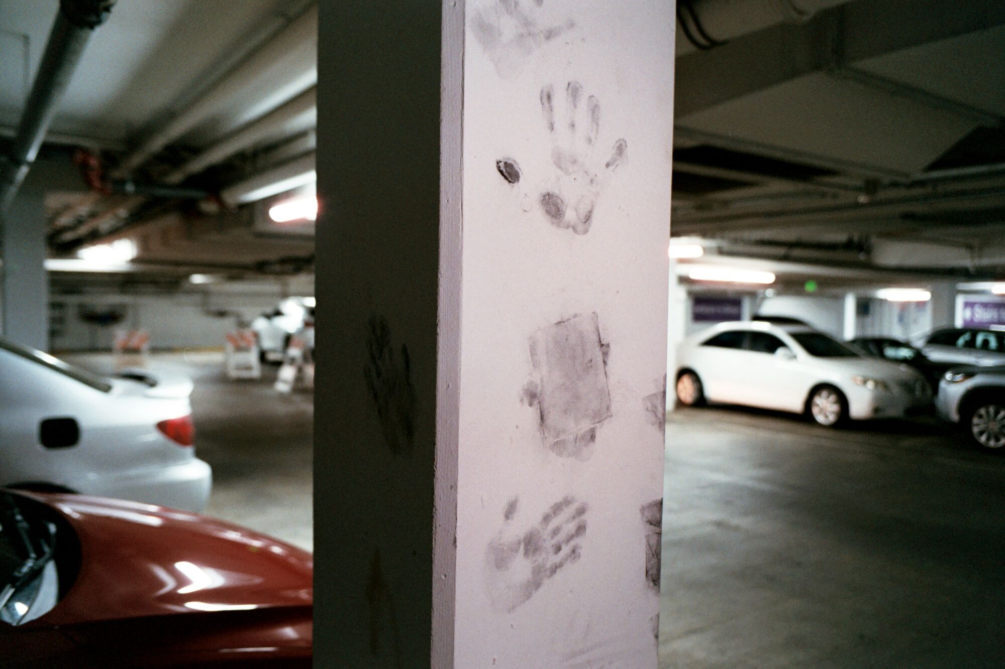 Gray handprints on a concrete column in a parking garage