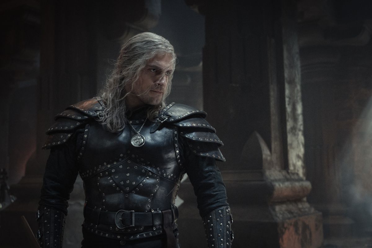 هنری کاویل با زره‌های بزرگ مشکی در منطقه‌ای از نوع قلعه ژست می‌گیرد و آماده مشت زدن به مردی در The Witcher است.