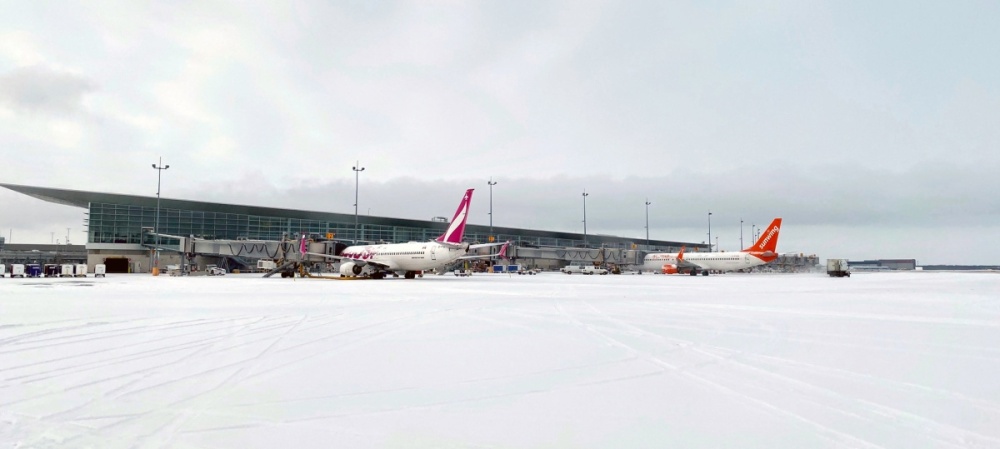 Swoop과 Sunwing 비행기는 위니펙 리차드슨 국제 공항의 탑승교에 눈 덮인 앞치마가 둘러 쌓여 있습니다.