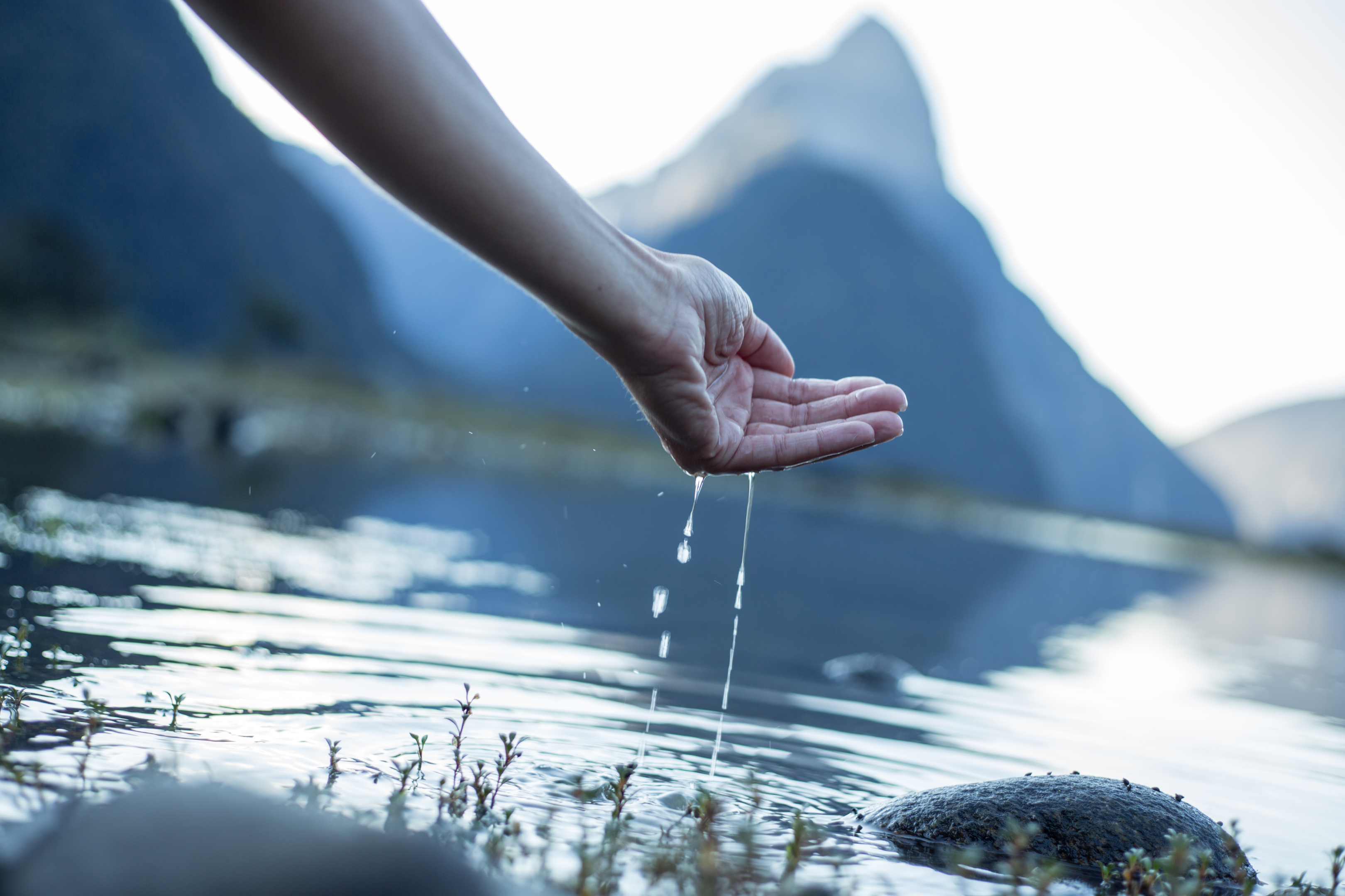 A hand cupped to catch the fresh water from the lake