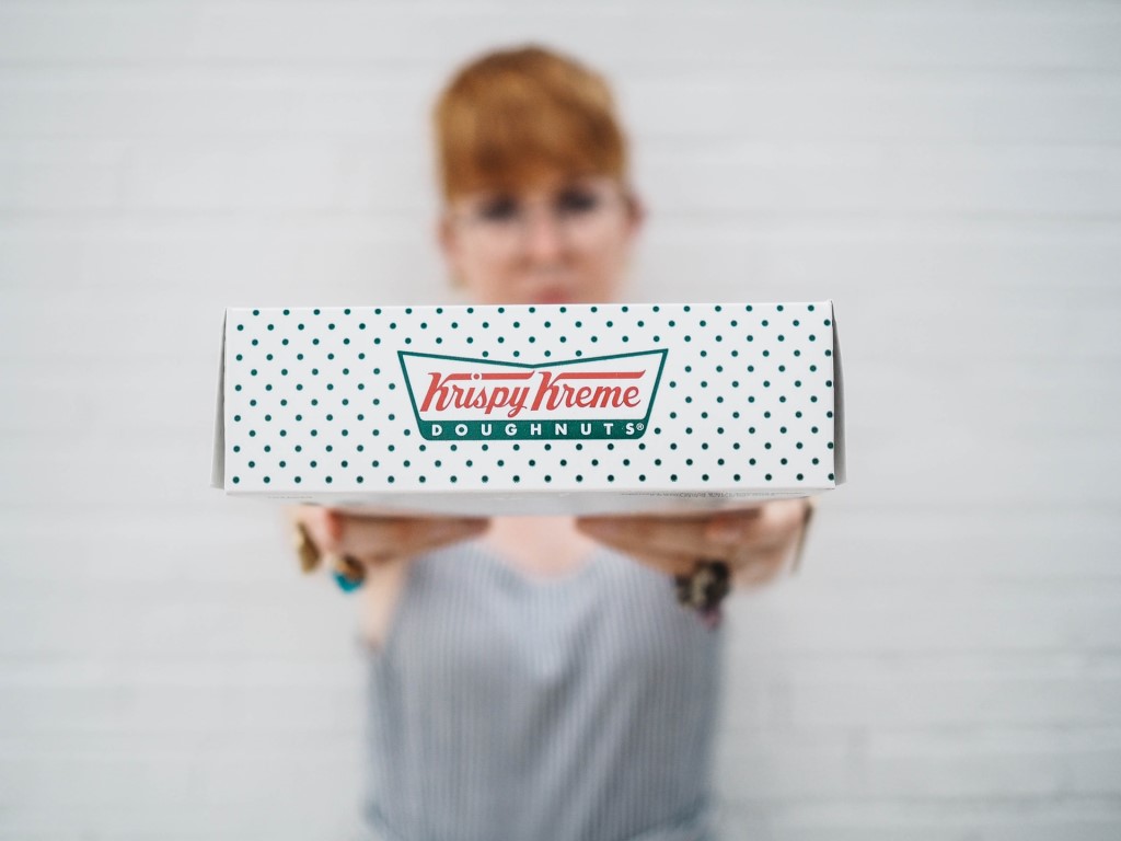 Woman holding out box of donuts at a Krispy Kreme fundraiser. School Fundraising Companies