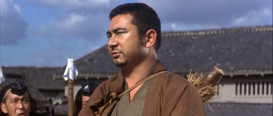 Shintaro Katsu as Zatoichi, the blind swordsman, with his eyes closed and carrying a pack on his back.