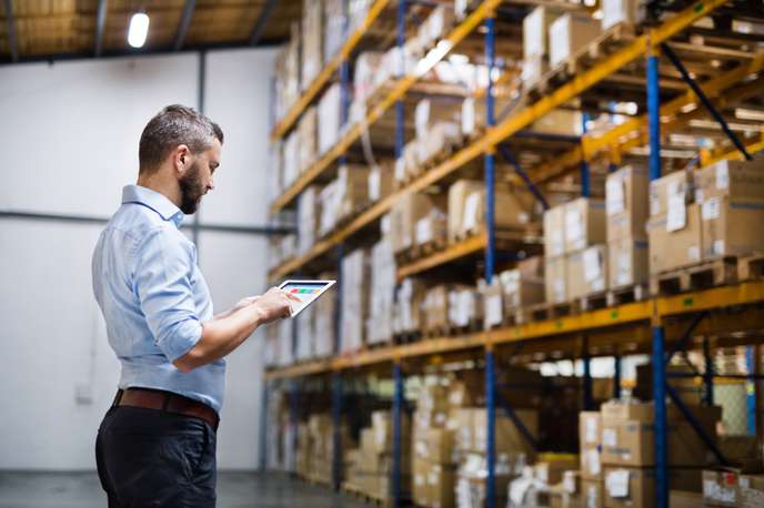 types of warehouse management system - A person using tablet in a warehouse