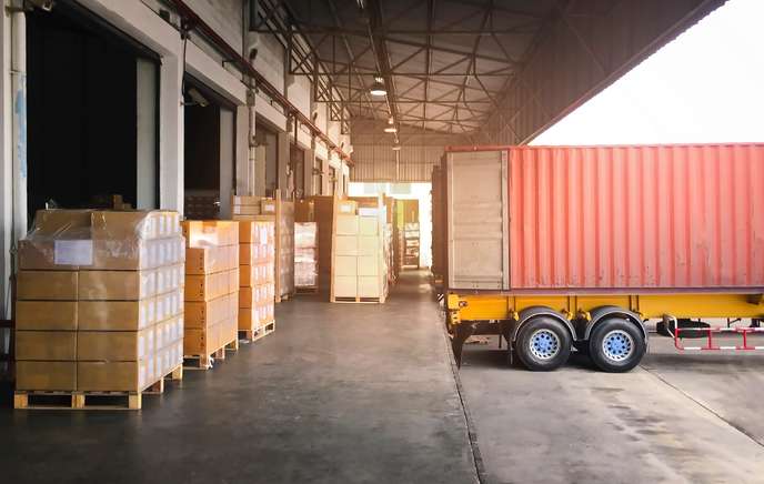 types of warehouse management system - A shipping cargo truck parked in a loading area of a warehouse