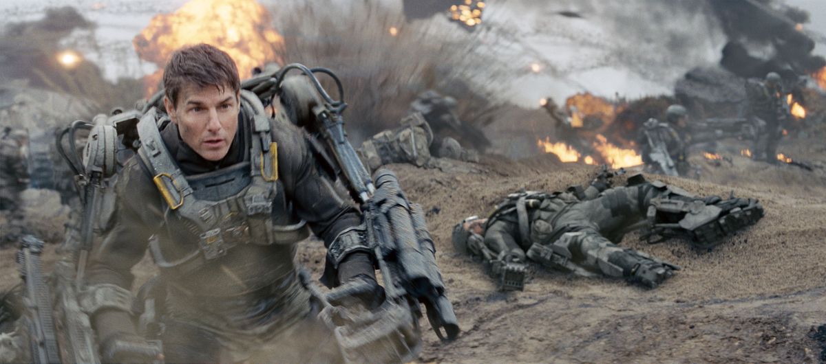 Tom Cruise as Cage in power armor storming a beach filled with explosions in Edge of Tomorrow.