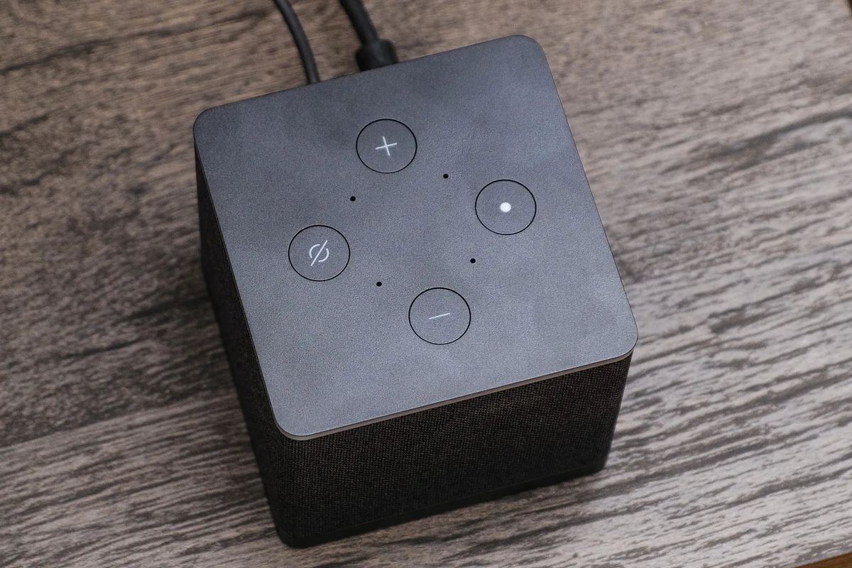 A top-down view of the Amazon Fire TV Cube, showing its microphones, plus four buttons for adjusting volume, and turning off the microphones.