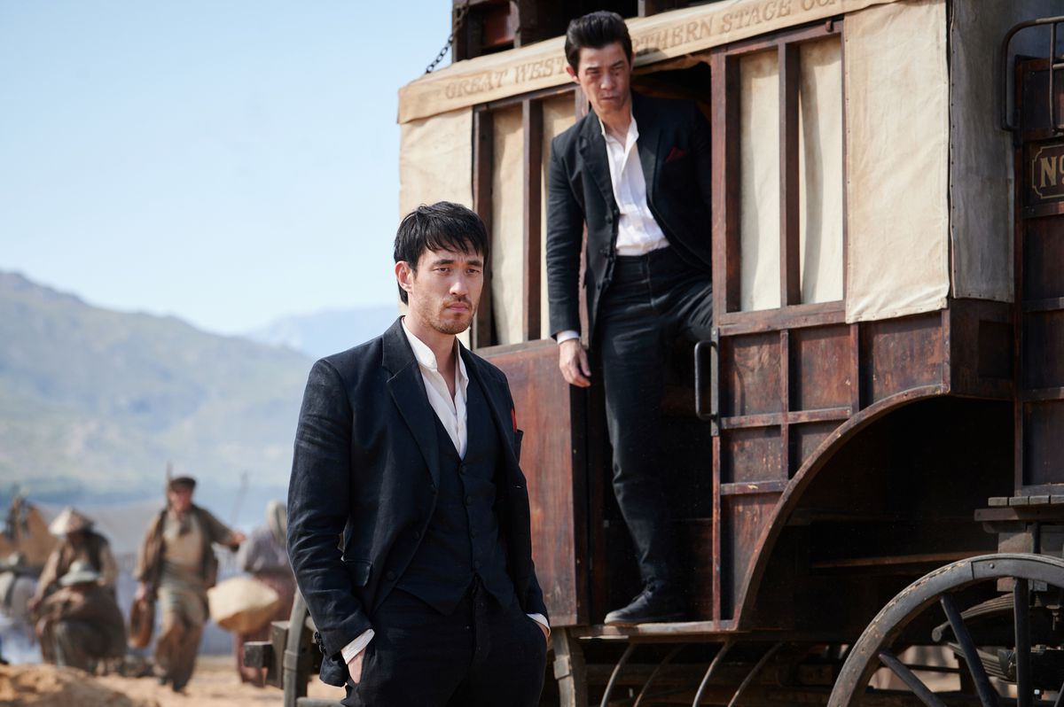 Andrew Koji and Jason Tobin exit a stagecoach wearing black suits in the desert in Warrior.