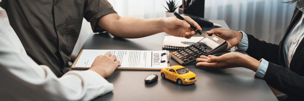 Car dealer calculate interest rate and costs of car loan with calculator, explaining details to customer on term and agreement in dealership office, offering financial and insurance service.