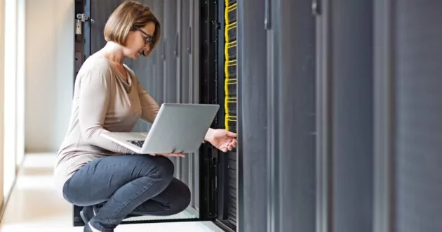 Brunette adult female employee working in internet server room of data warehouse