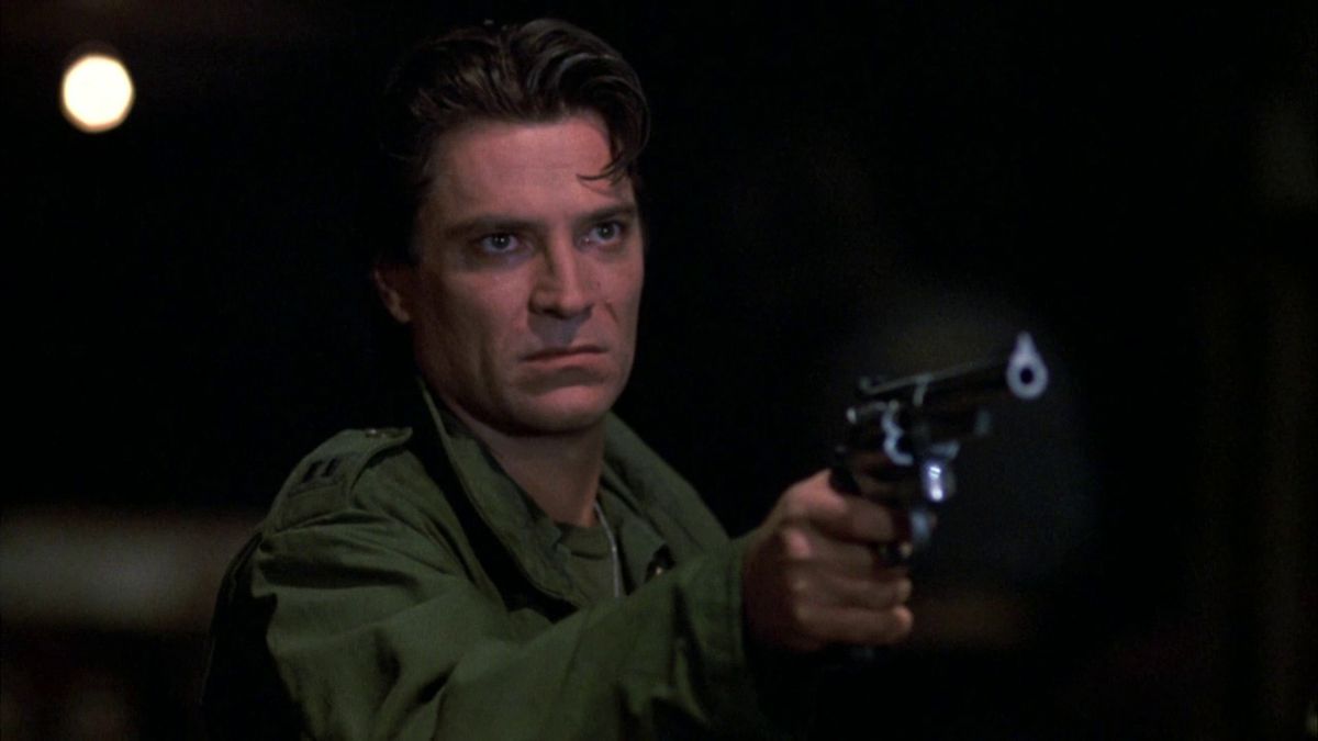 Joe Pilato, wearing a green army jacket, points a revolver in Day of the Dead.