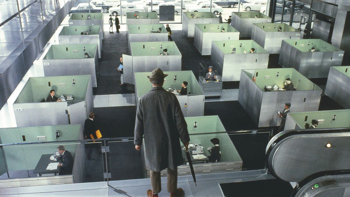Monsieur Hullot (Jacques Tati) staring down at a room filled with cubicles in Playtime.