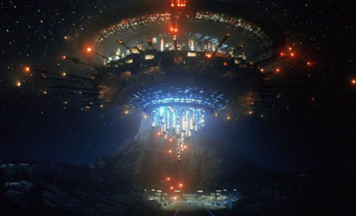 A giant spaceship hovering above a small valley with a mountain in the distance in Close Encounters of the Third Kind.