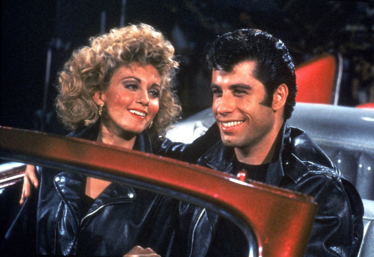 (L-R) Olivia Newton-John and John Travolta behind the wheel of a car in Grease.