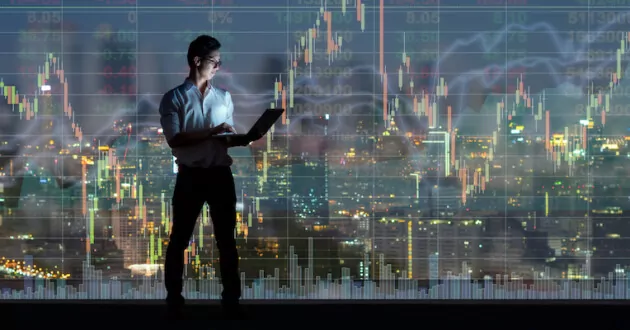 Asian businessman standing and using the smart mobile phone showing the Stock market chart over the cityscape background at night time, Business technology and trading concept