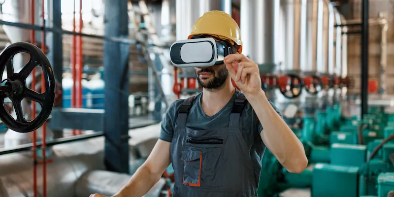 A young Caucasian male engineer is using virtual reality glasses to check on the system stats.