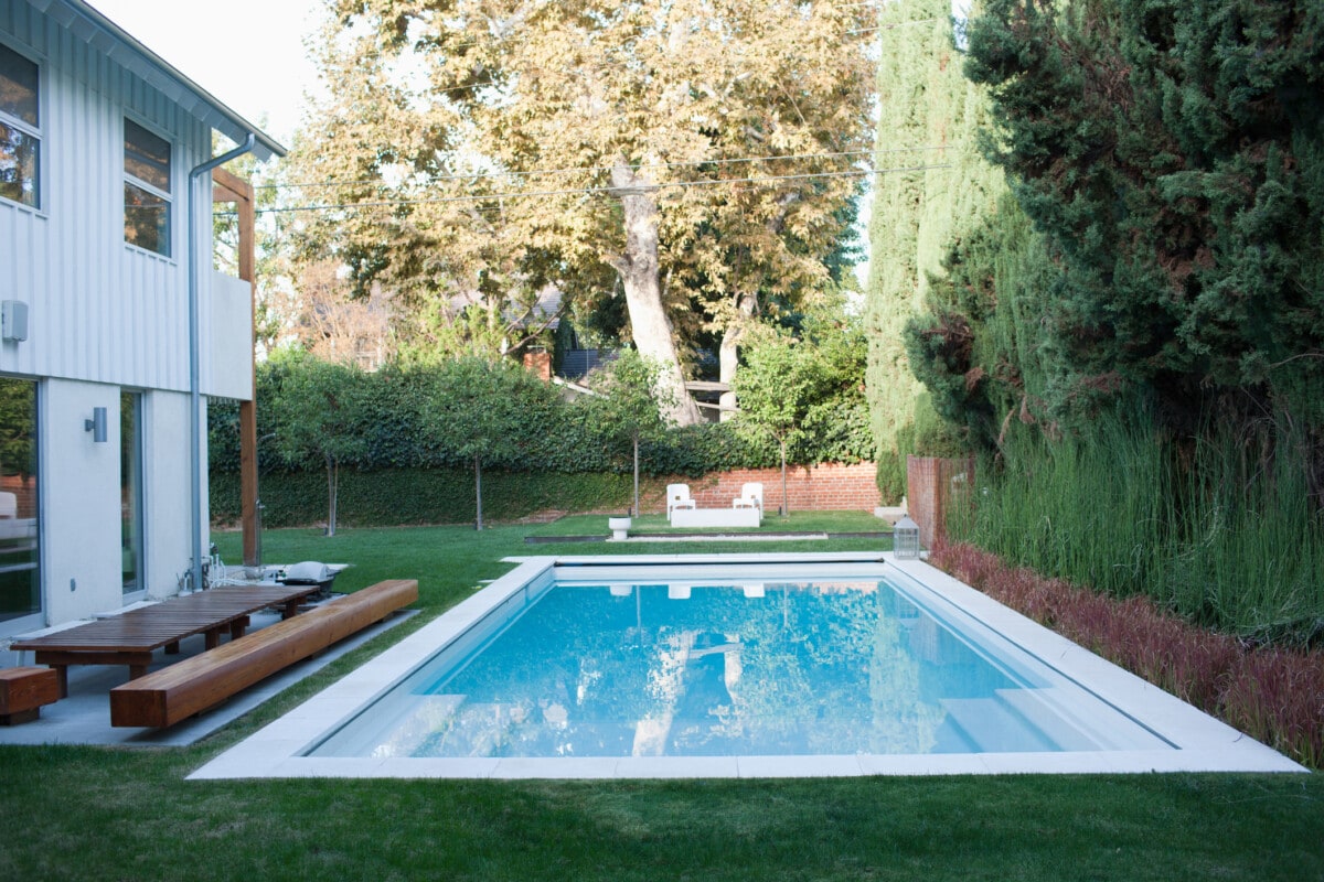 Modern wooden lounge chair next to swimming pool california house _ getty
