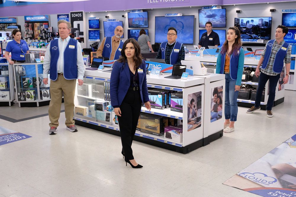 the cast of superstore gathers around a bunch of tvs, mouths agape