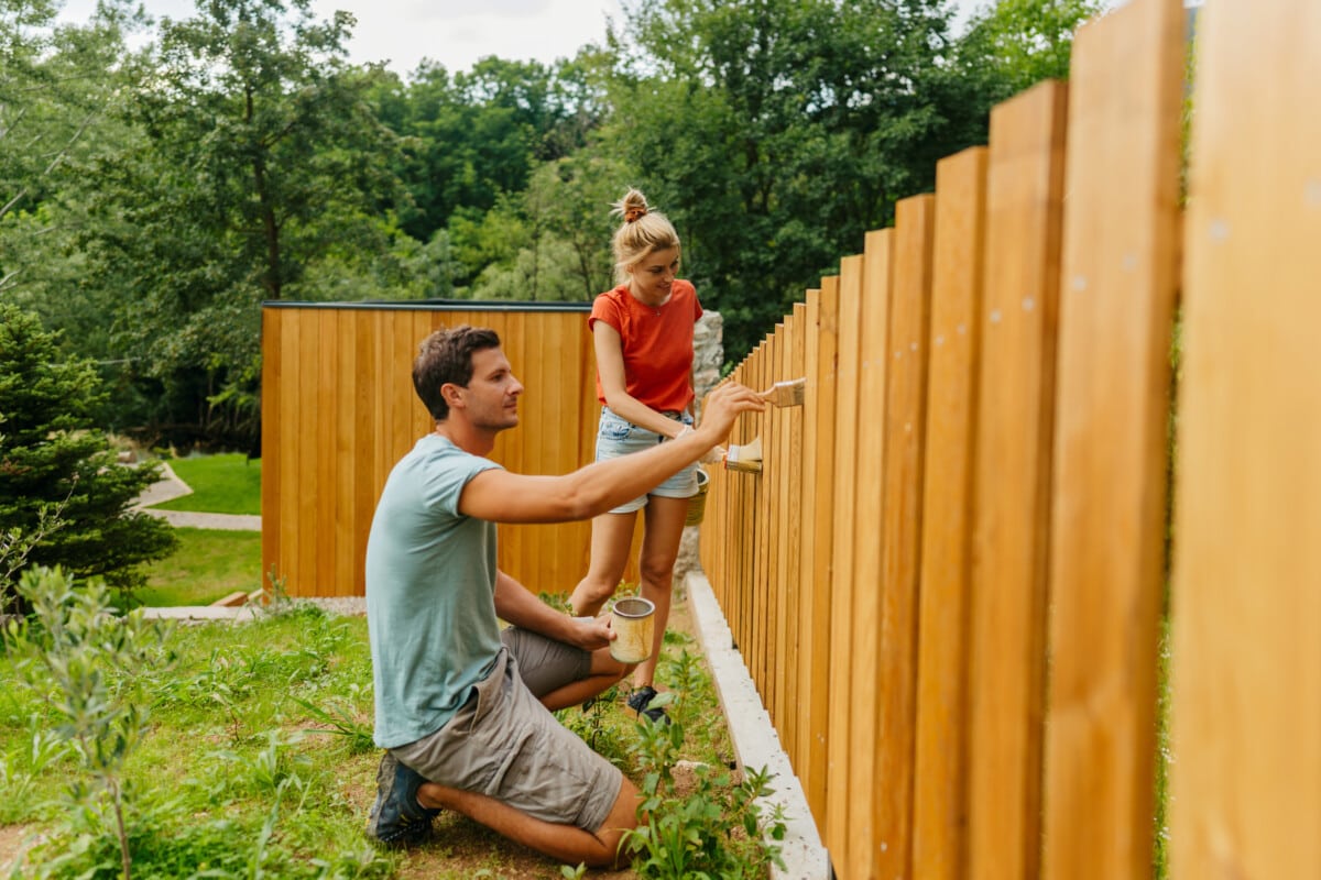 couple painting a picket fence