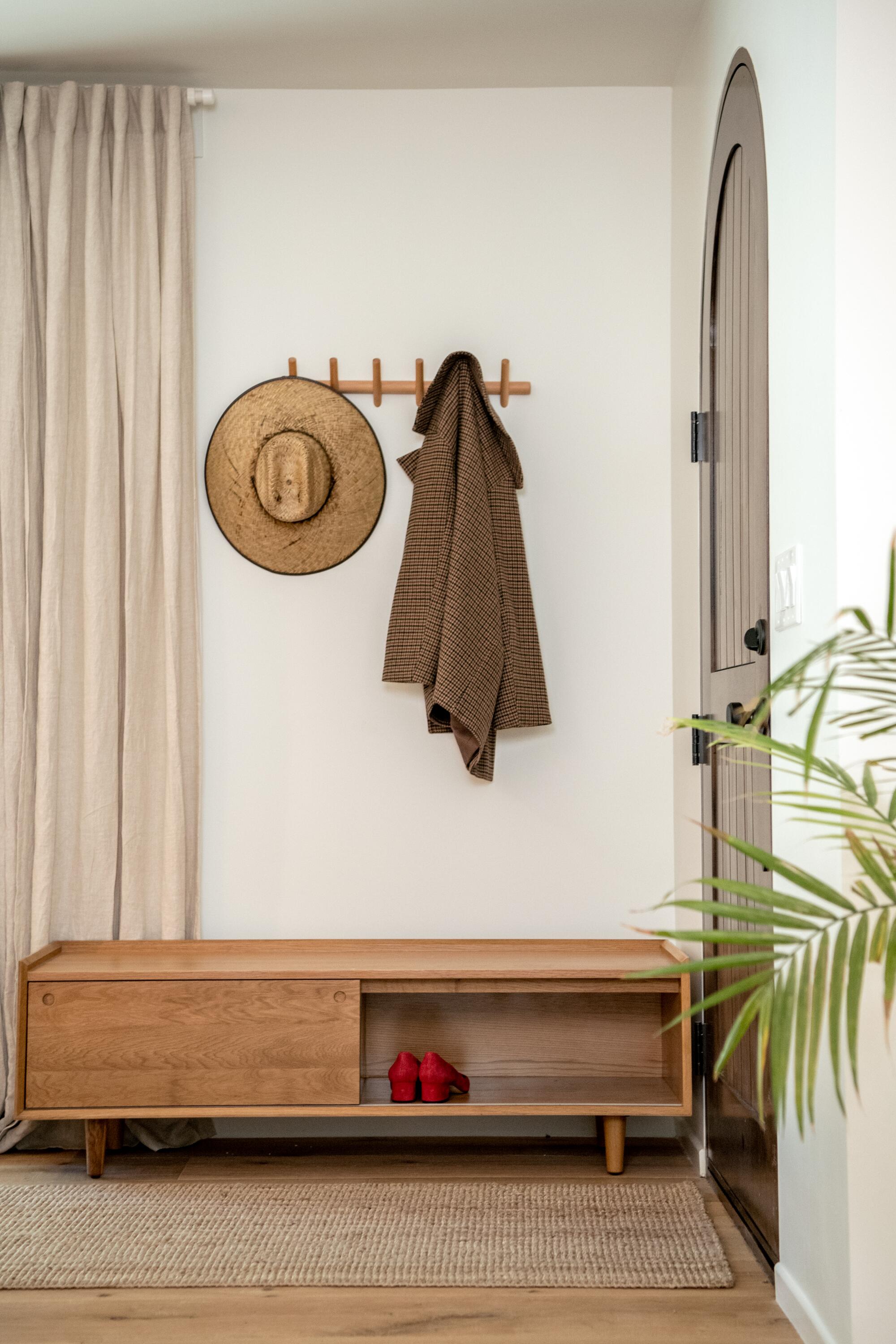 A hat and jacket hang on the wall in a tiny vestibule by a door.