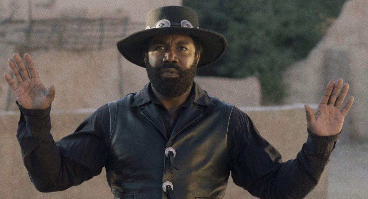 Michael Jai White holds his hands up in surrender in his all-black outfit from Outlaw Johnny Black.
