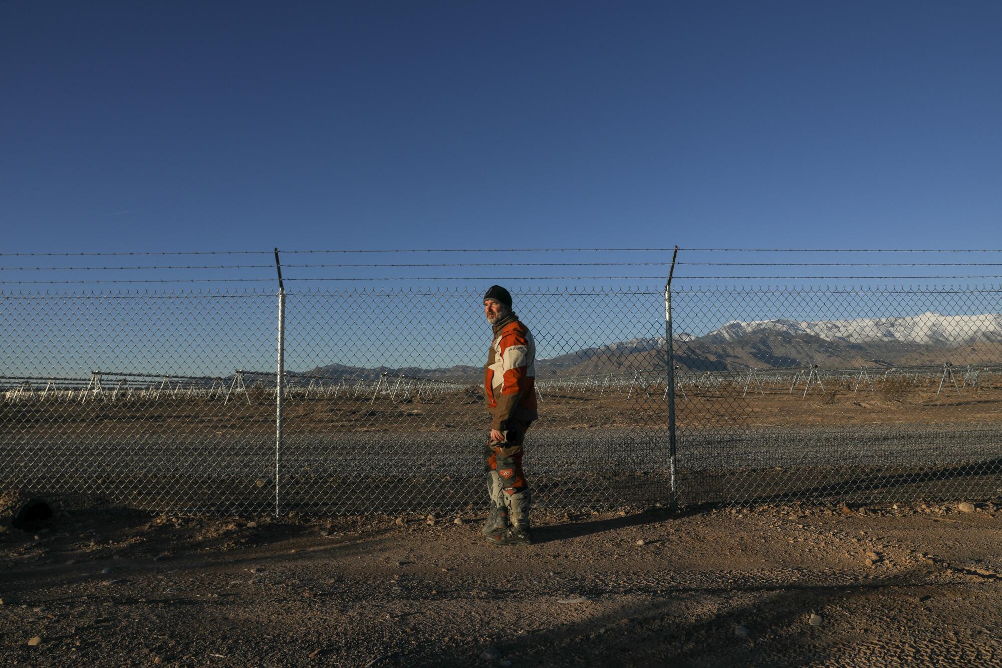 Jimmy Lewis pauses at the fence line at a massive solar plant under construction in the desert near his home in Pahrump, Nev.