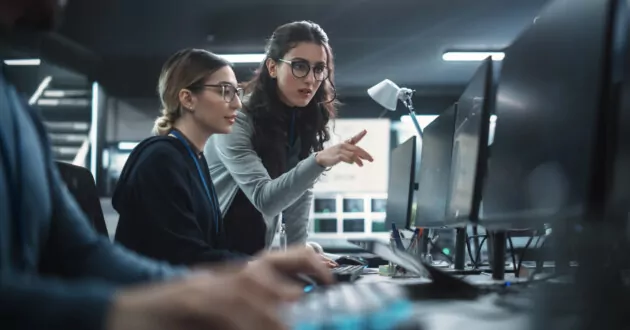 Two Women Working in a Cyber Security Software Development Department. Young Manager Updating Software Developer on the Artificial Intelligence Safety Project