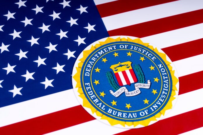 The seal of the Federal Bureau of Investigation with the US flag, on 26th March 2018. The FBI is the domestic intelligence and security service of the US.