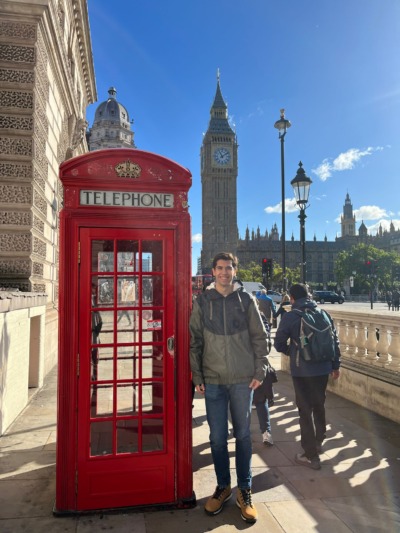 David dựa vào hộp thư màu đỏ trước Big Ben ở London.