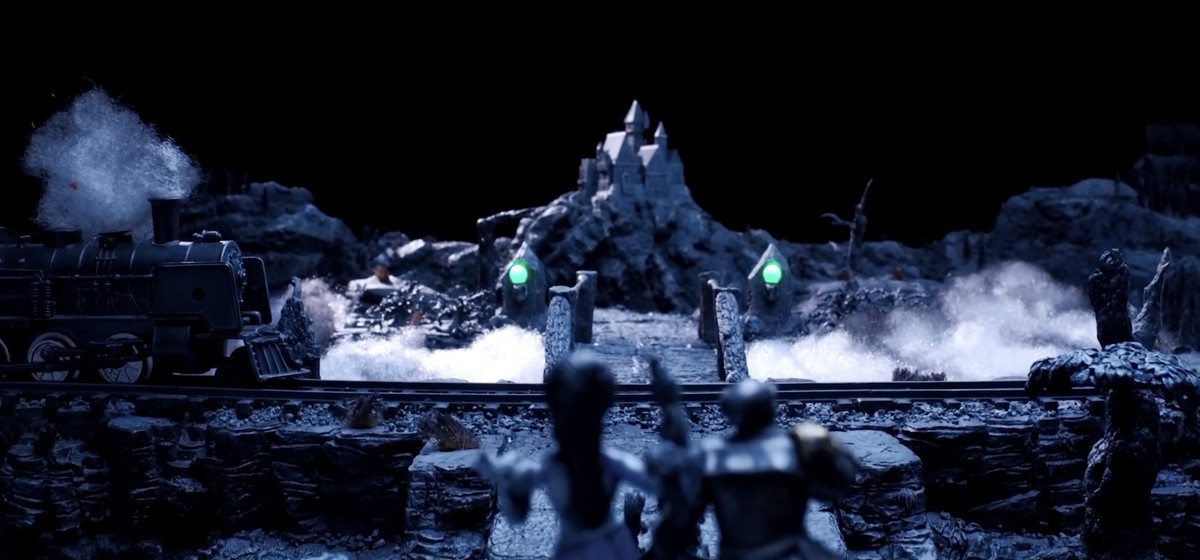 Miniatures in Coffin Run depict Dracula’s castle, a tiny steam engine with cotton ball exhaust, and figures riding atop a stage coach, all built in greyscale lit with tiny sickly green lamps. 