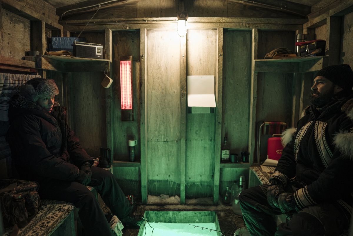 Navarro (Kali Reis) sitting with Qavvik (Joel Montgrand) in his fishing hut, telling him about her mom