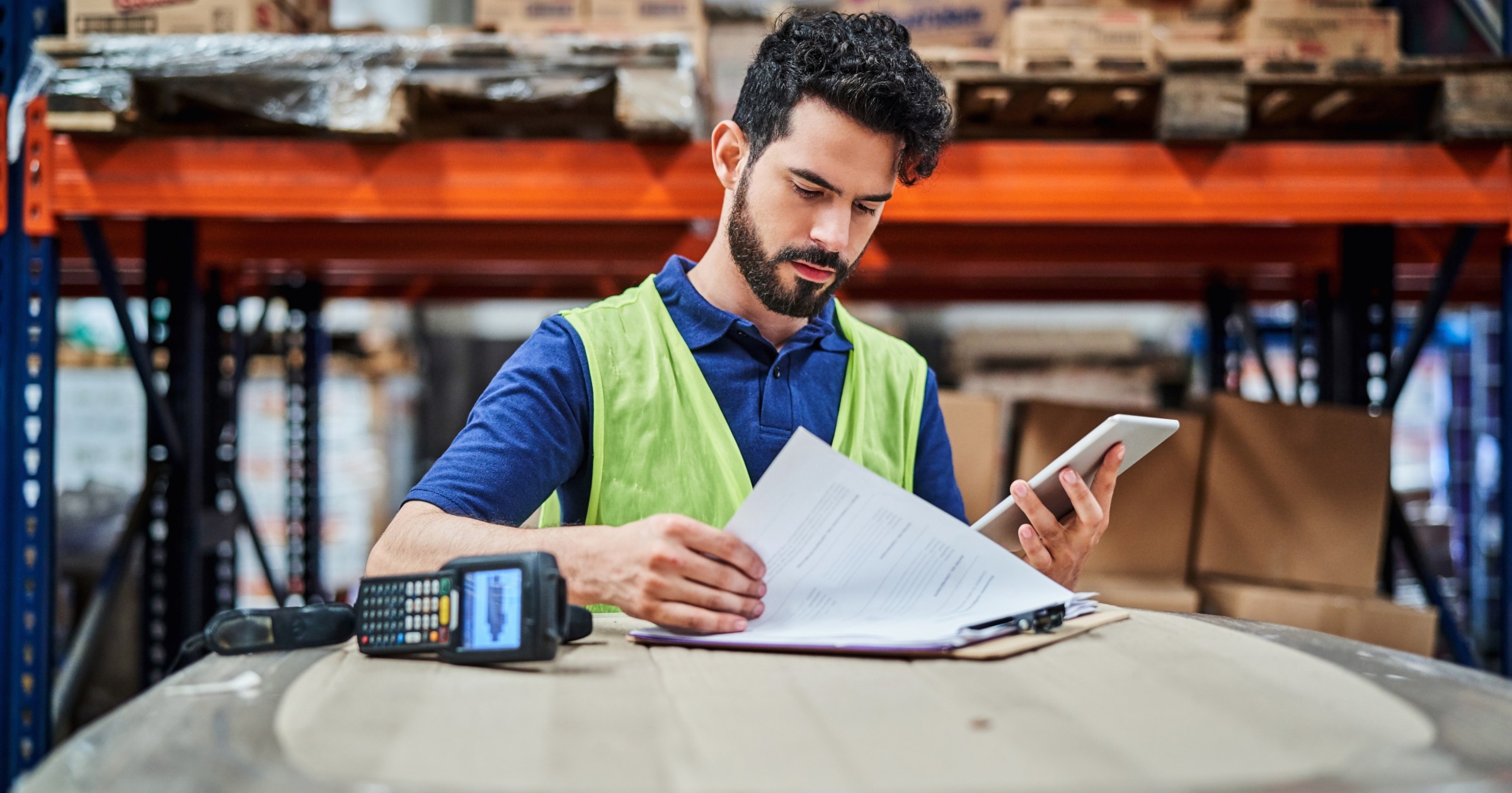 Production worker looking through clipboard and checklist while holding phone