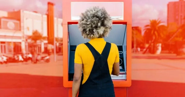 Человек в комбинезоне пользуется красным банкоматом