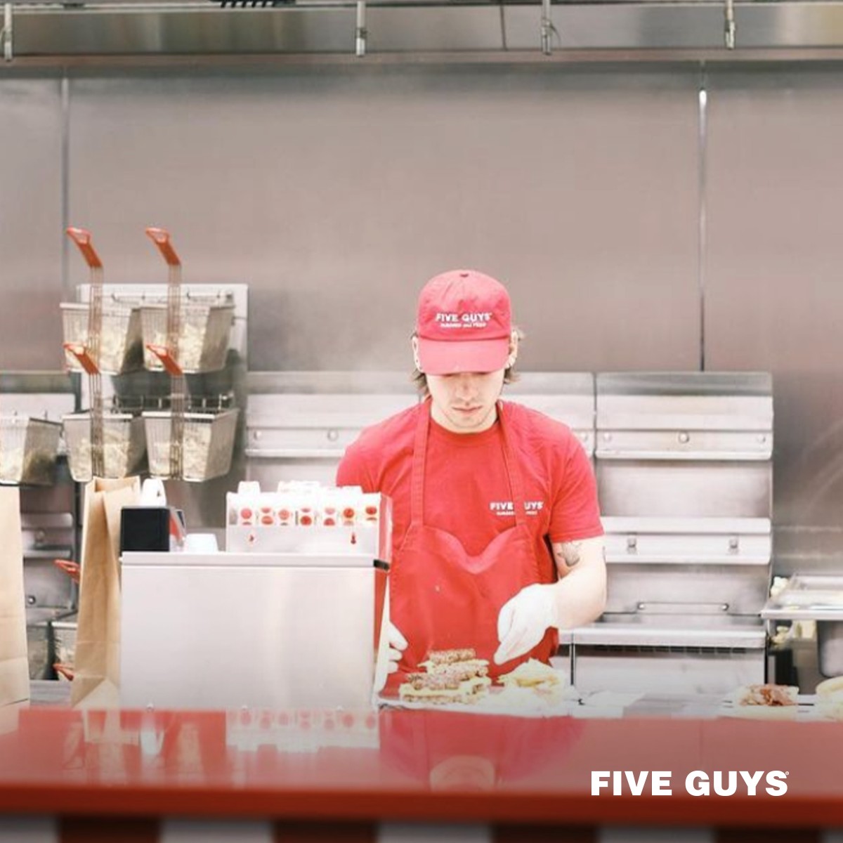 Five guys worker making burgers at a Five Guys Fundraiser