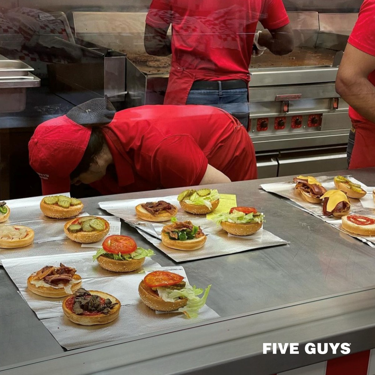 Five guys worker making burgers at a Five Guys fundraiser