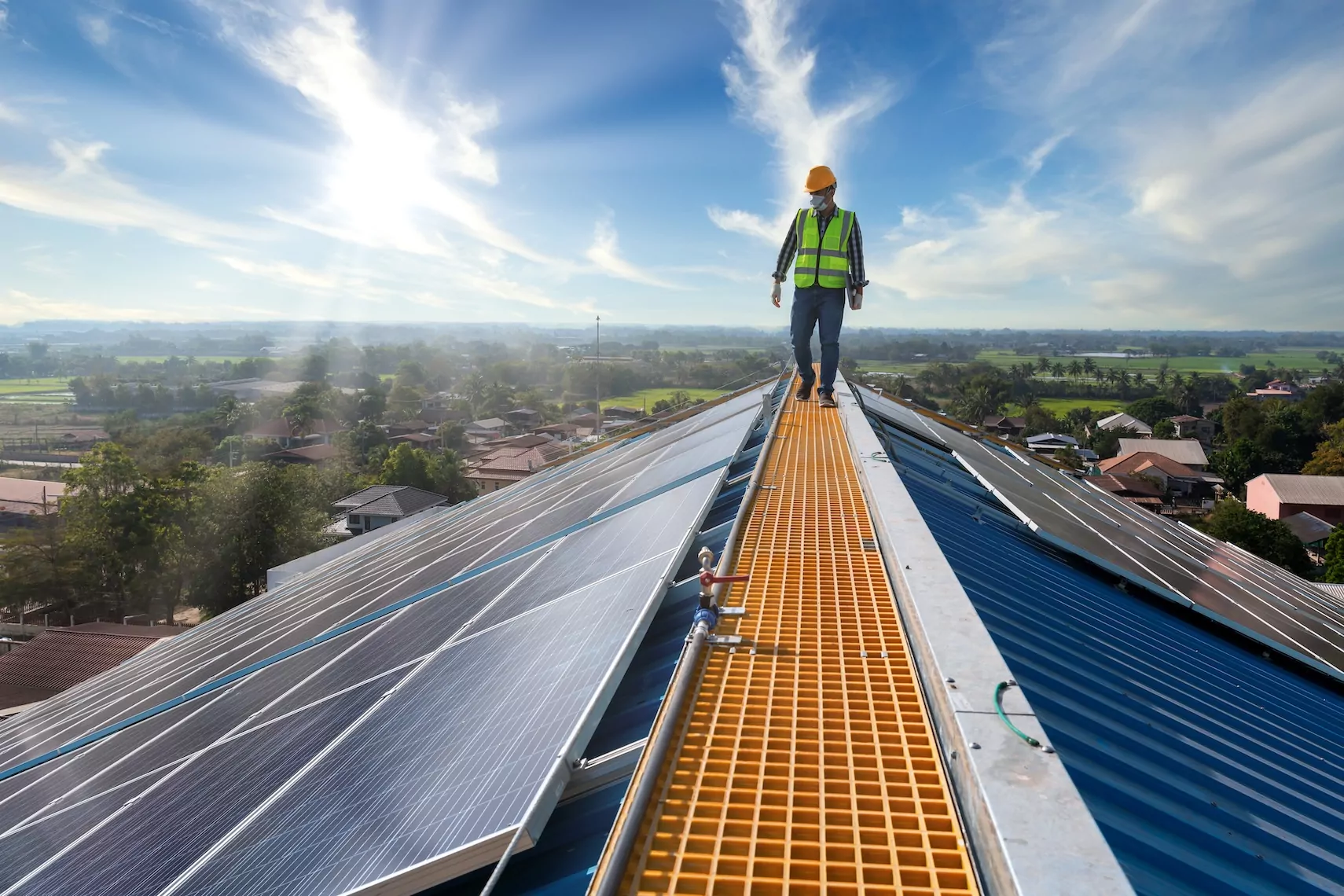 Technician walking on solar paneled roof with sunlight in the background