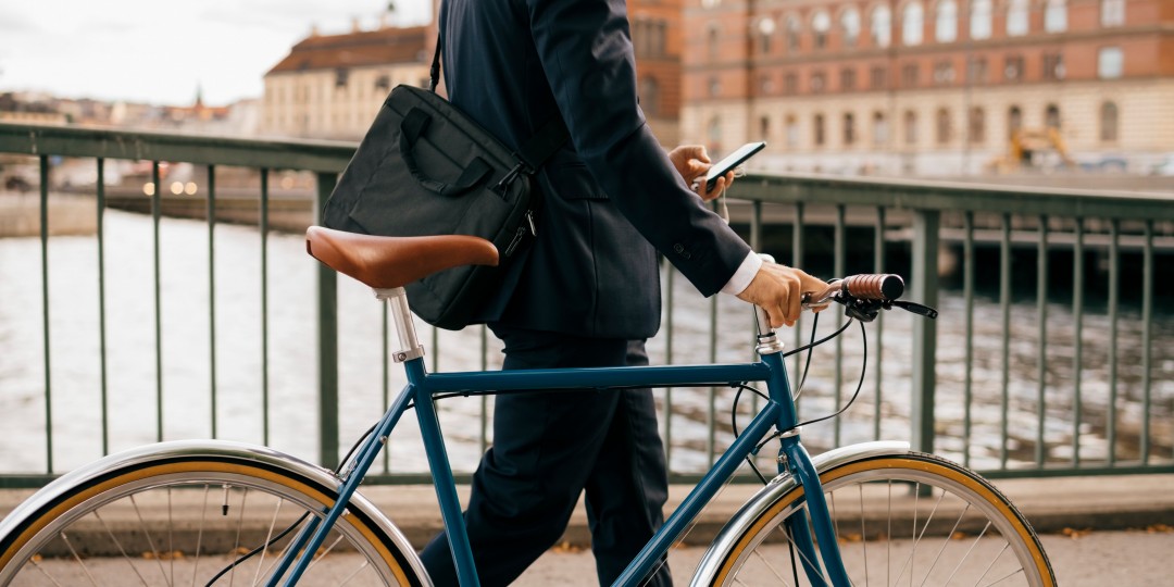 Man walking with bicycle while on phone.