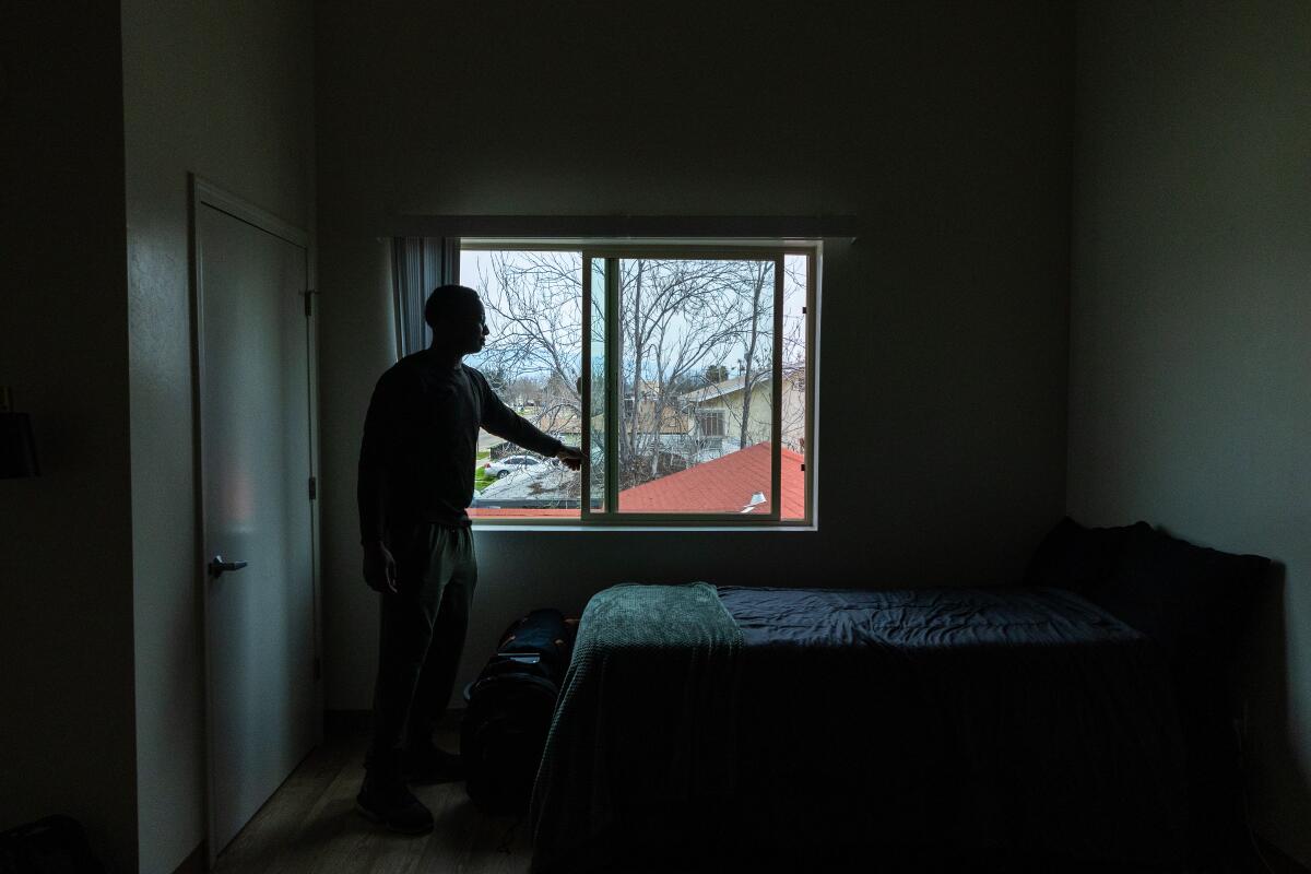 A young man opens the window in a tidy apartment. 