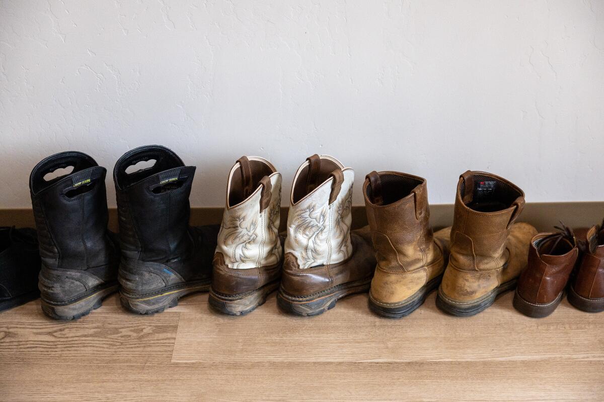 A close-up of boots neatly lined up along an apartment wall. 