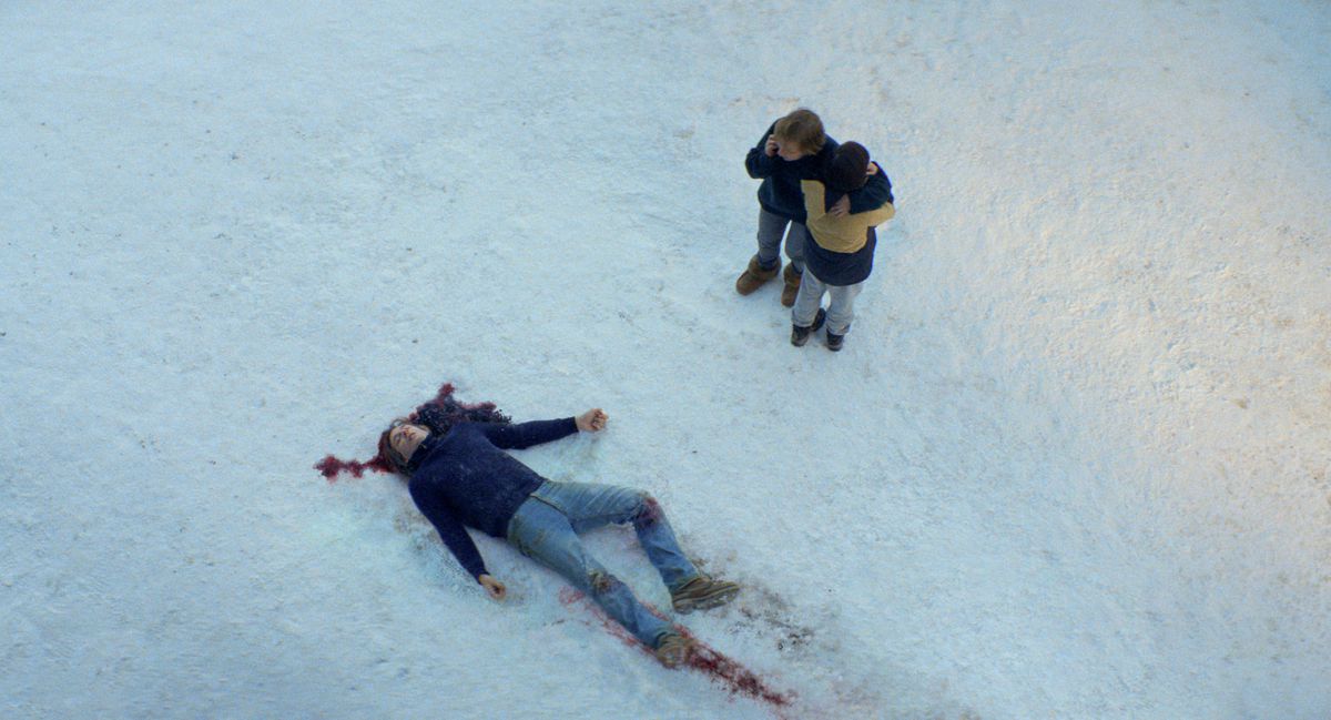 Een dood, bebloed lichaam in de sneeuw in Anatomy of a Fall, terwijl iemand bijna aan de telefoon is