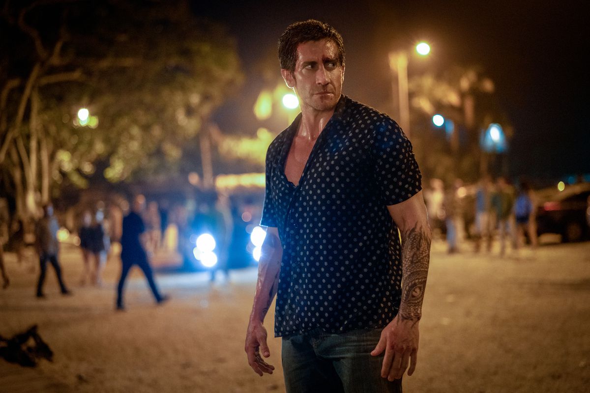 Een man in een overhemd met knopen staat 's nachts op straat.