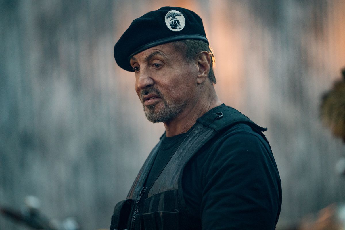 Een middenshot van Sylvester Stallone die een zwarte baret en vest draagt ​​in de film Expend4bles.
