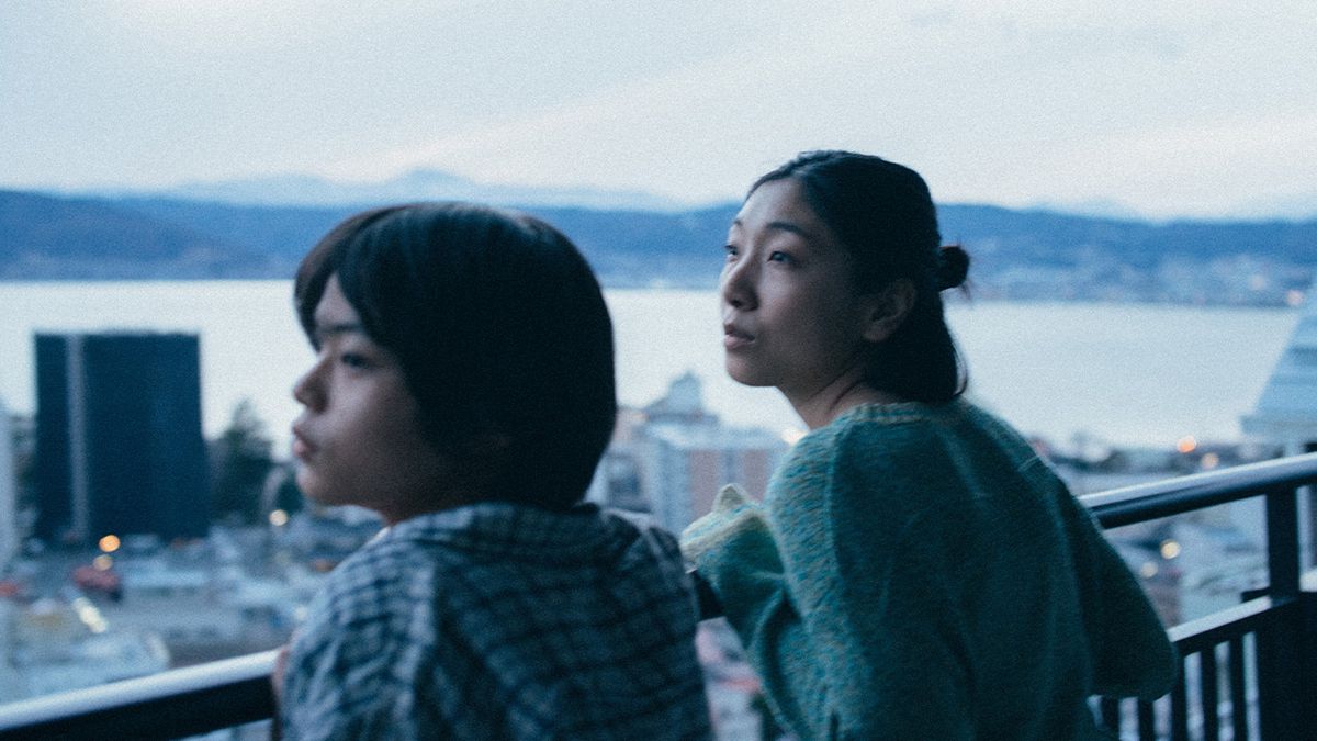 Sakura Andō e Sōya Kurokawa apoiam-se em uma grade sobre uma paisagem urbana em Monster