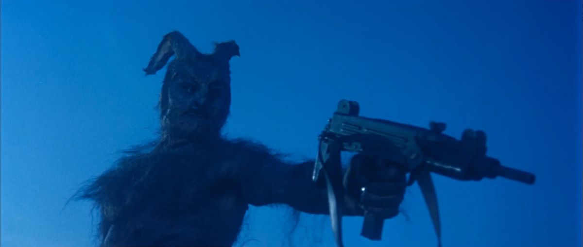 A demonic horned creature holding a MAC-10 SMG against a blue sky.