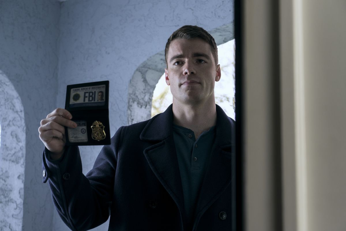 Gabriel Basso holds out his FBI badge in The Night Agent