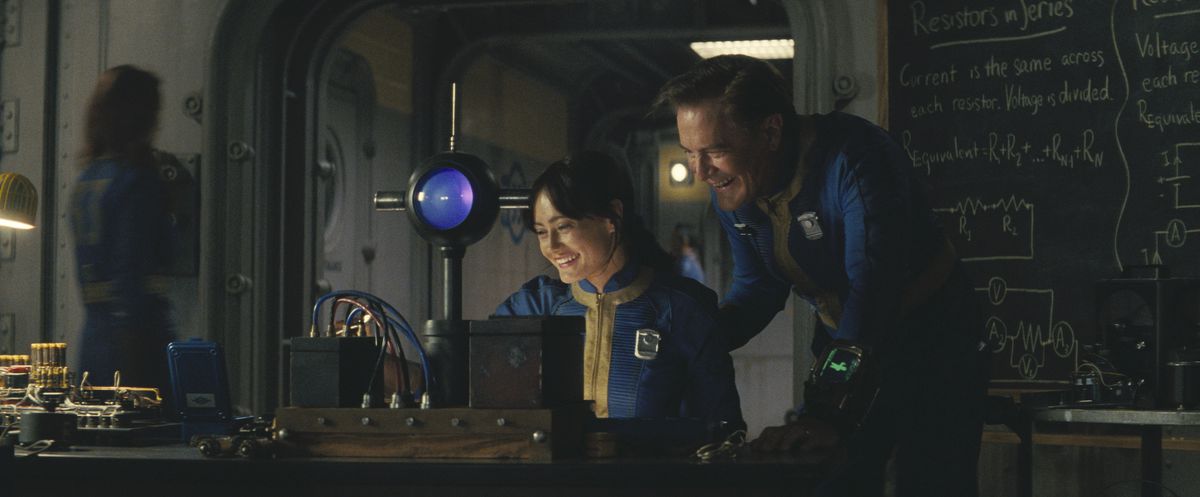 Lucy (Ella Purnell) and her dad, Overseer Hank (Kyle Maclachlan) laughing over a science experiment in a still from Fallout season 1