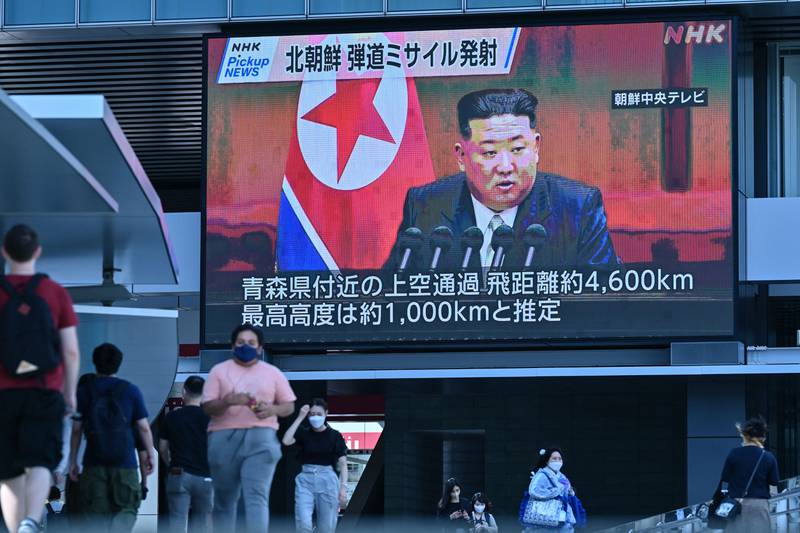 Pešci hodijo pod velikim videozaslonom, na katerem so prikazane slike severnokorejskega voditelja Kim Jong Una med objavo novic v Tokiu 4. oktobra 2022.